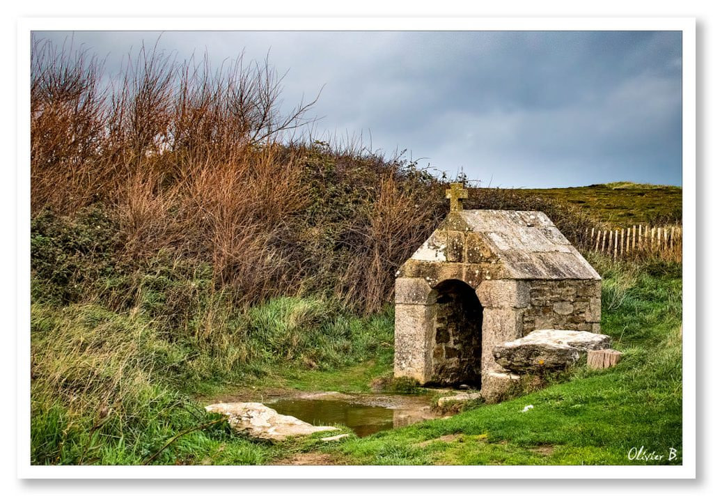 Ancien lavoir en granit au milieu de la lande, entouré d&#039;ajonc et surmonté d&#039;une croix