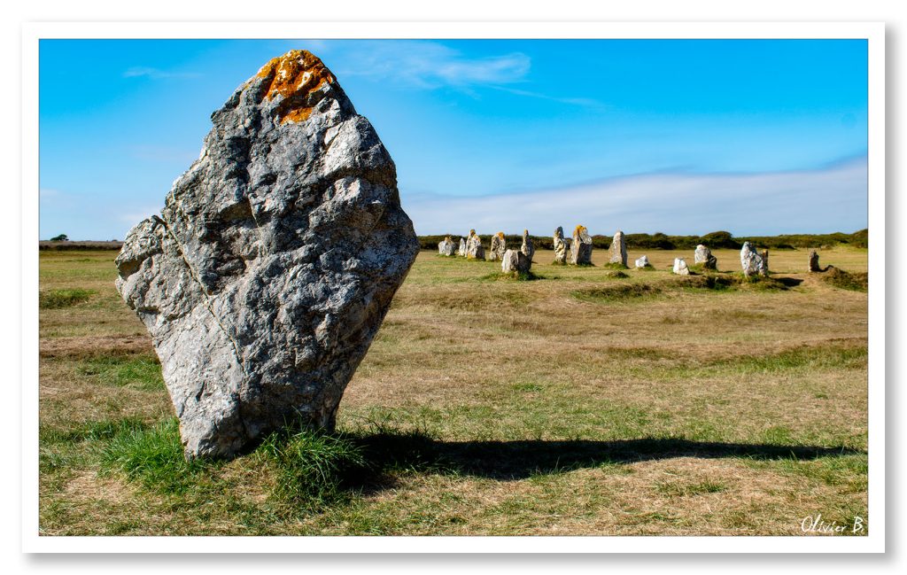 Imposant menhir à Camaret-sur-Mer sous un ciel azur, drapé de lichen doré