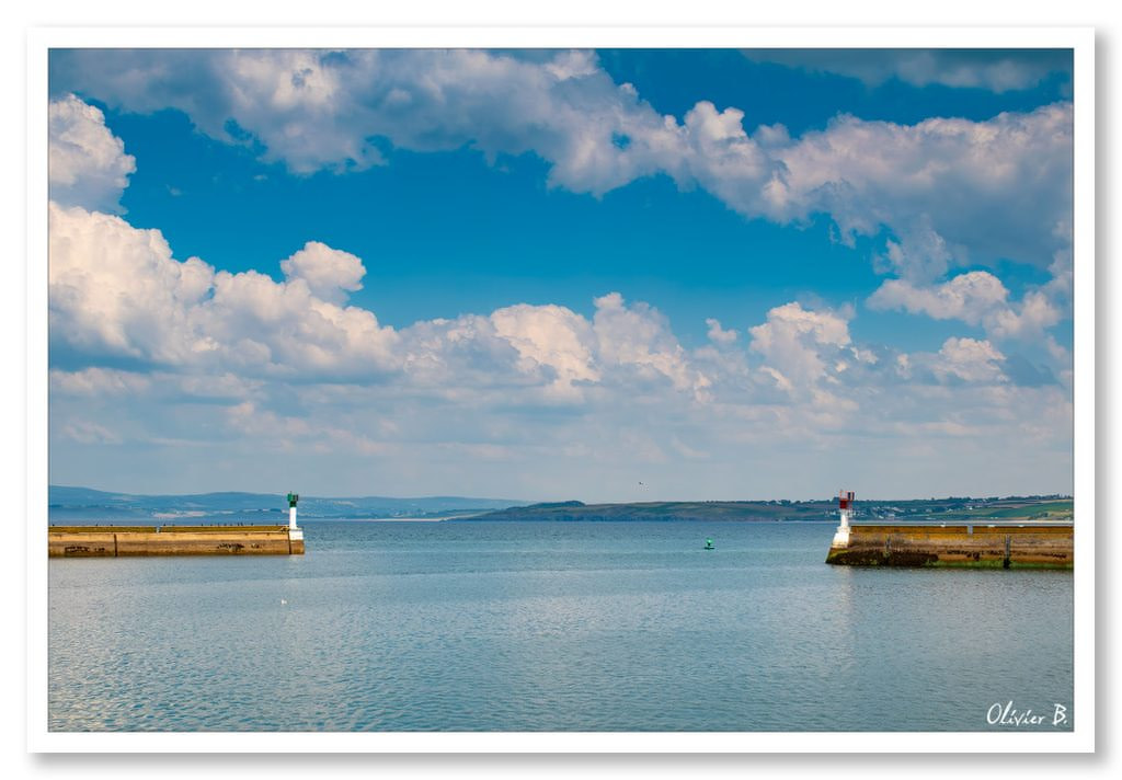 Entrée du port de pêche de Douarnenez sous un ciel cotonneux, mettant en valeur les deux digues