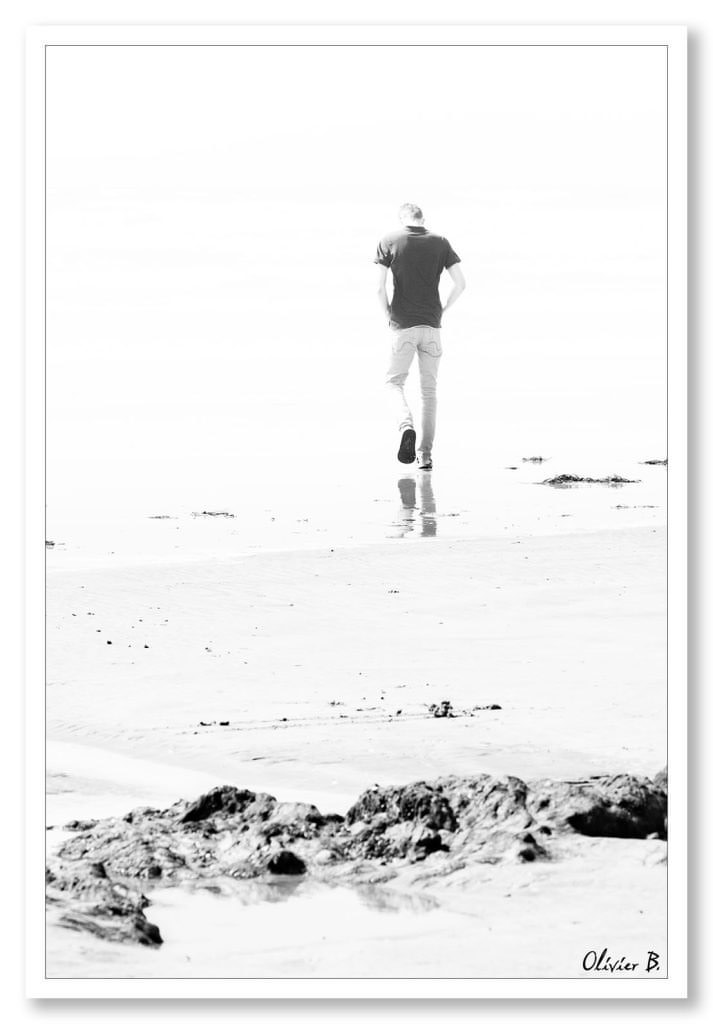 Un homme avance résolument sur une plage, créant une scène highkey captivante