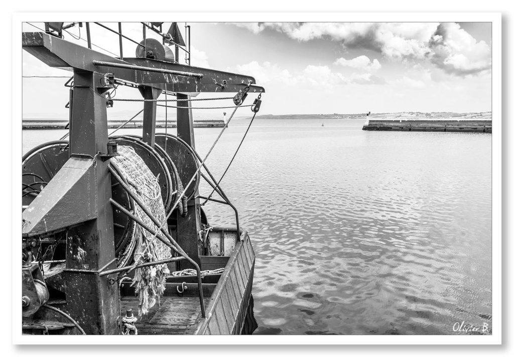 Un chalutier amarré au port de pêche de Douarnenez sous un ciel aux nuages capricieux