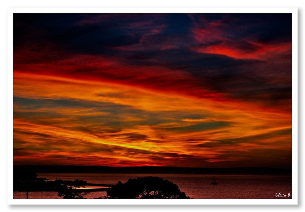 Vue enflammée du port de Douarnenez sous un ciel aux teintes rouges et jaunes