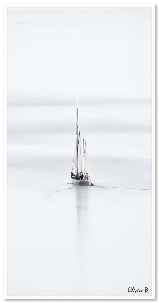 Un voilier évoque un songe, glissant doucement sur les douces vagues, son reflet s&#039;étirant à l&#039;horizon