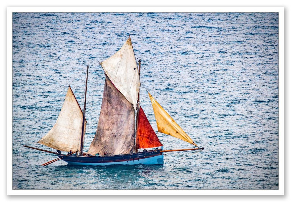 Un vieux chalutier aux voiles multicolores, tel un arc-en-ciel en mer